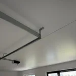 Biely, matný napínací strop inštalovaný nad garážovou bránou