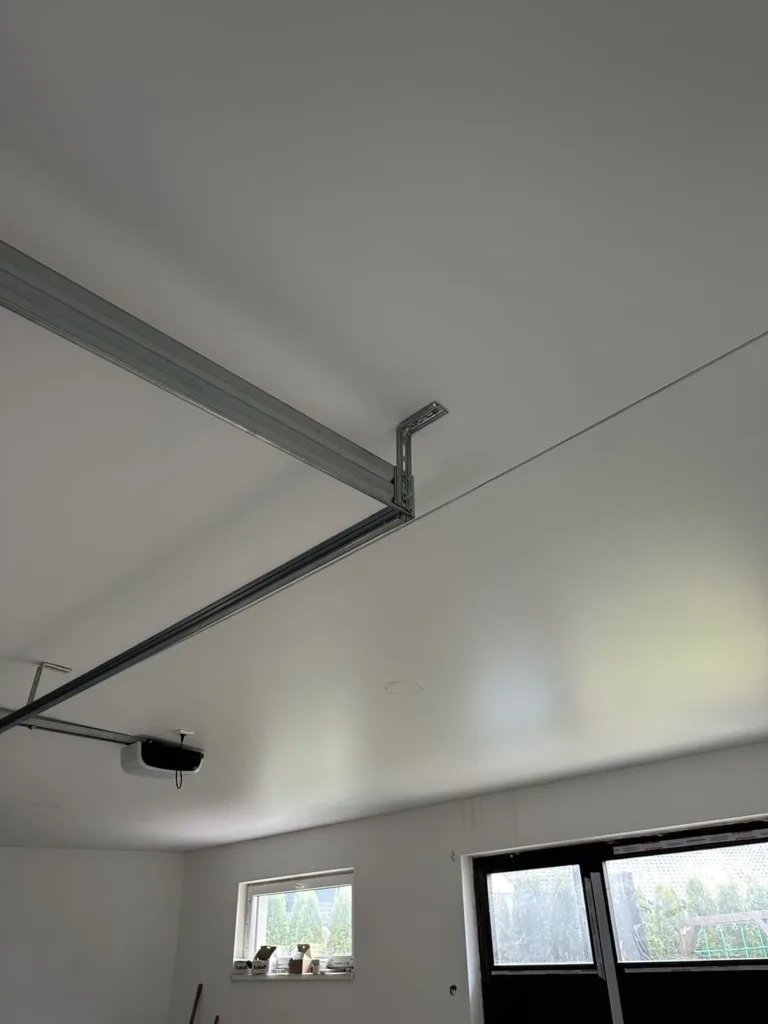 Biely, matný napínací strop inštalovaný nad garážovou bránou