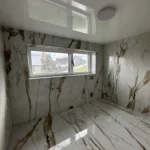 Biely lesklý napínací strop v kúpeľni rodinného domu, navyše s jedným svietidlom