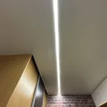 Lineárne osvetlenie s teplým bielym svetlom dotvárajúce atmosféru obývačky rodinného domu