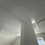 Podkrovie rodinného domu s nainštalovaným lesklým napínaným stropom